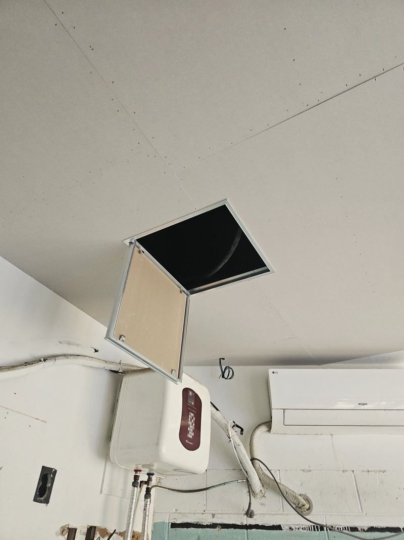 석고보드 천장에 설치된 점검구 문짝이 열려 내부 프레임이 보이는 모습